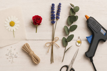 A flat lay showing different types of preserved flowers created using various methods: a pressed daisy, silica gel dried rose, air-dried lavender bundle, glycerin treated eucalyptus, and a small resin embedded flower pendant