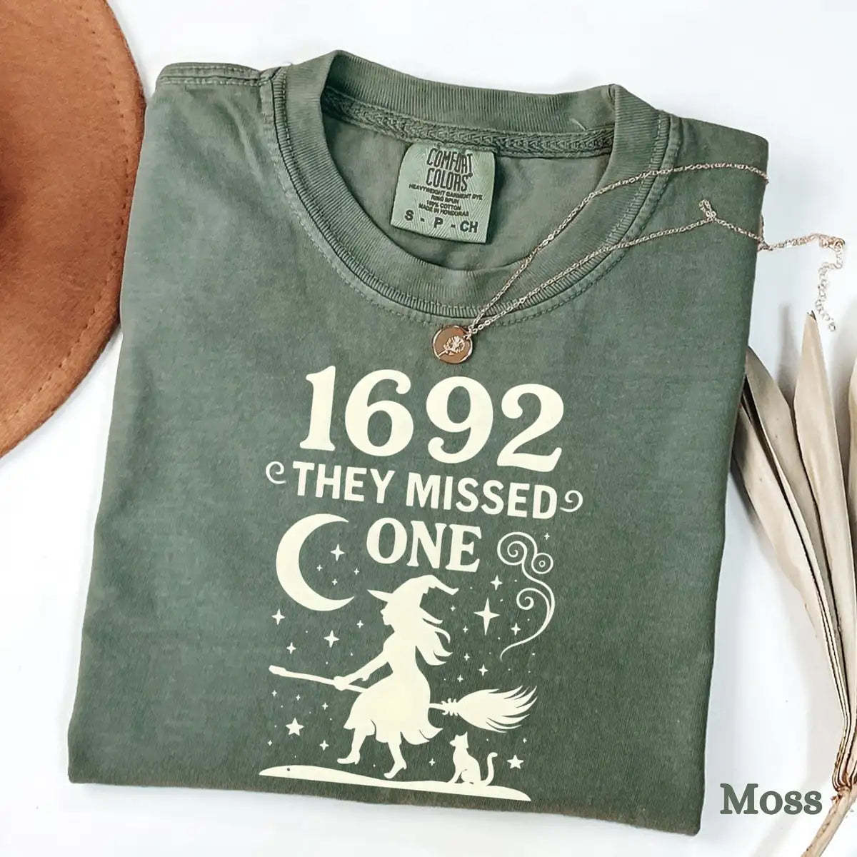 Comfort Colors T-shirt in Moss color featuring 1692 They Missed One flying witch graphic