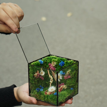 Hexagonal decorative item with floral design held by a person against a neutral background