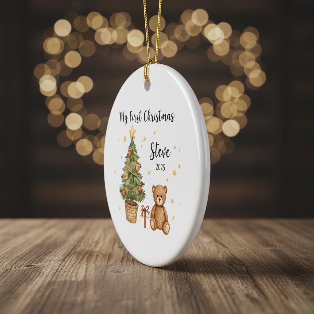 Decorative ornament with a Christmas tree and teddy bear design, featuring the text 'My First Christmas Steve 2025', on a wooden surface with a blurred light background.