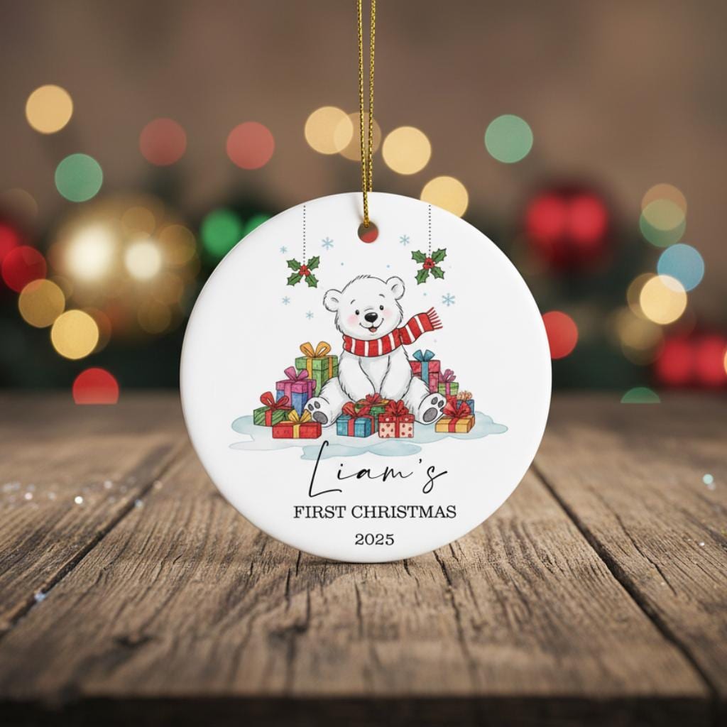 Personalized Christmas ornament with a bear and presents on a wooden surface with festive lights in the background.