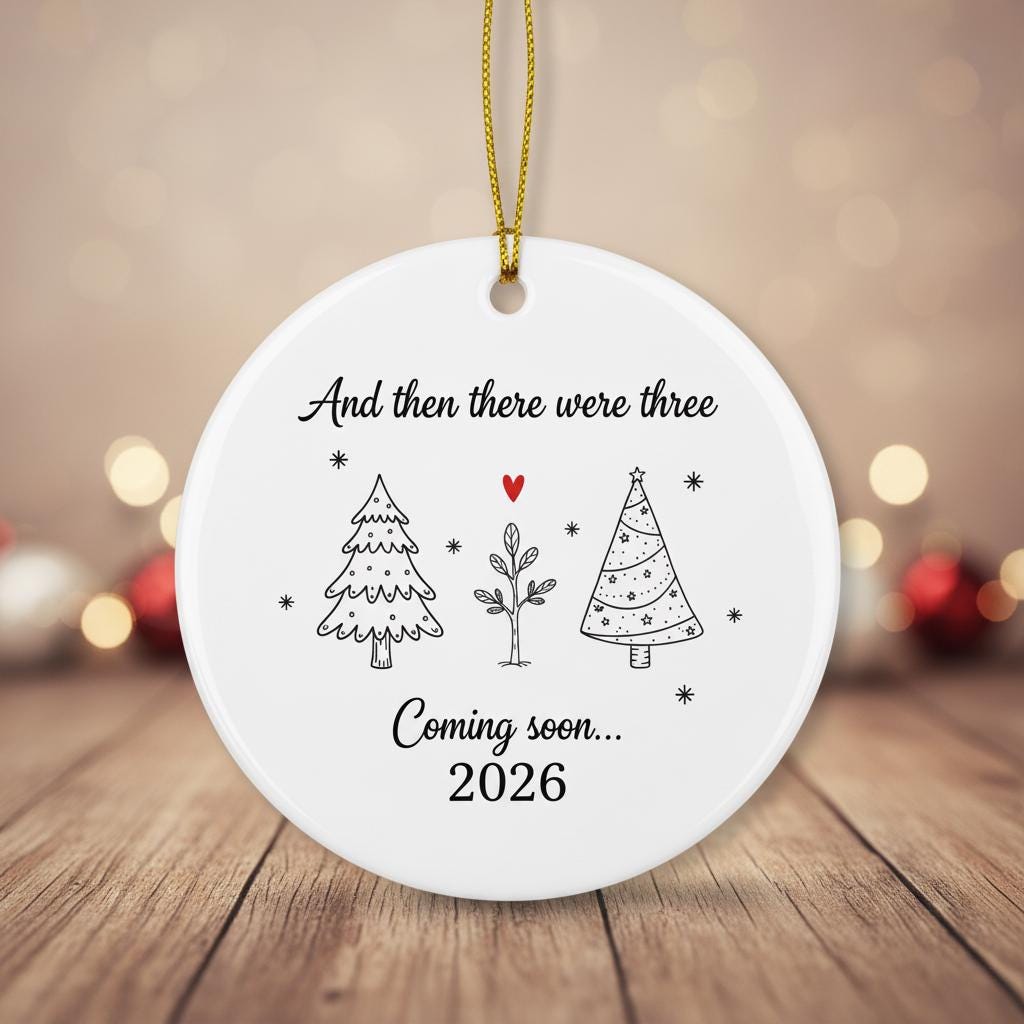 Round ceramic ornament with text and tree illustrations on a wooden surface with blurred lights in the background