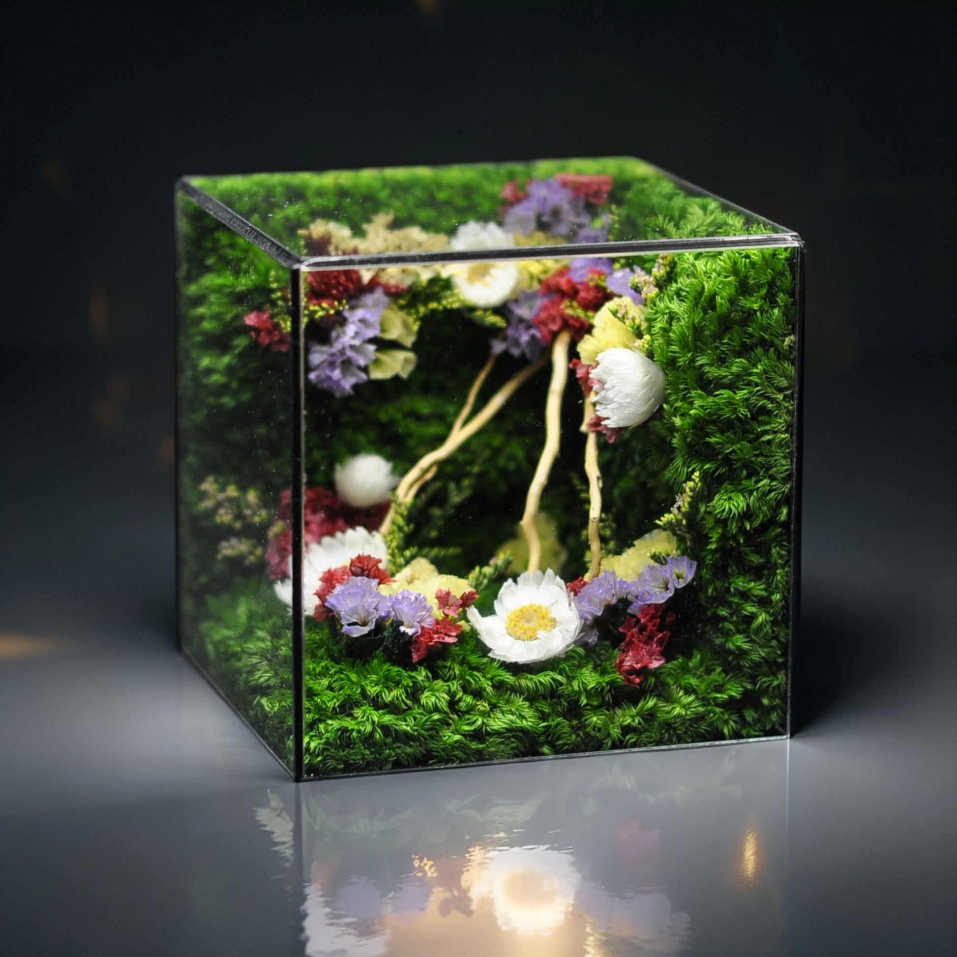 Square glass container with a floral arrangement on a dark background