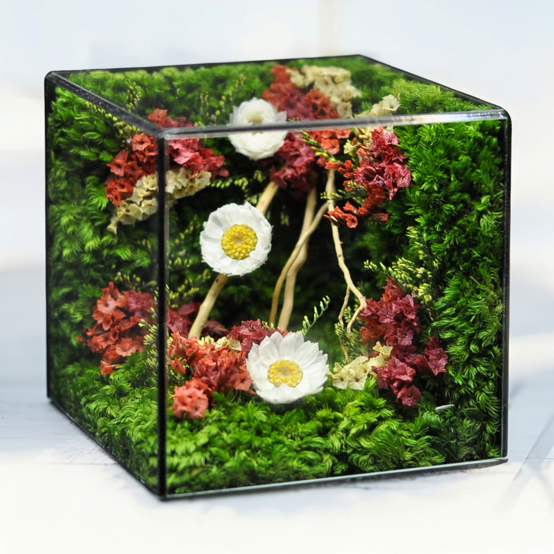 Decorative cube with artificial flowers and greenery on a white background