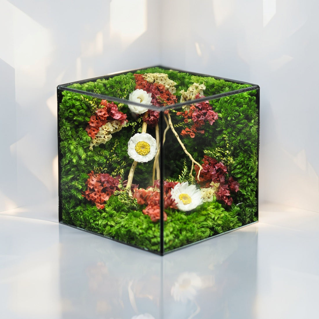 Decorative cube with artificial flowers and greenery on a white background