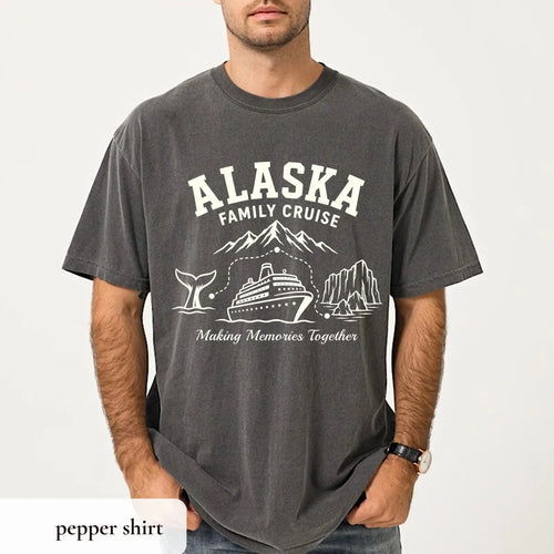 Man in a Pepper Comfort Colors tee and a wristwatch, white Alaska Family Cruise arch over mountains, a whale tail and a ship