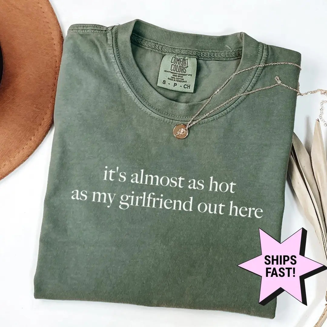 Folded Moss green Comfort Colors tee with the two-line almost as hot as my girlfriend quote in white serif lettering