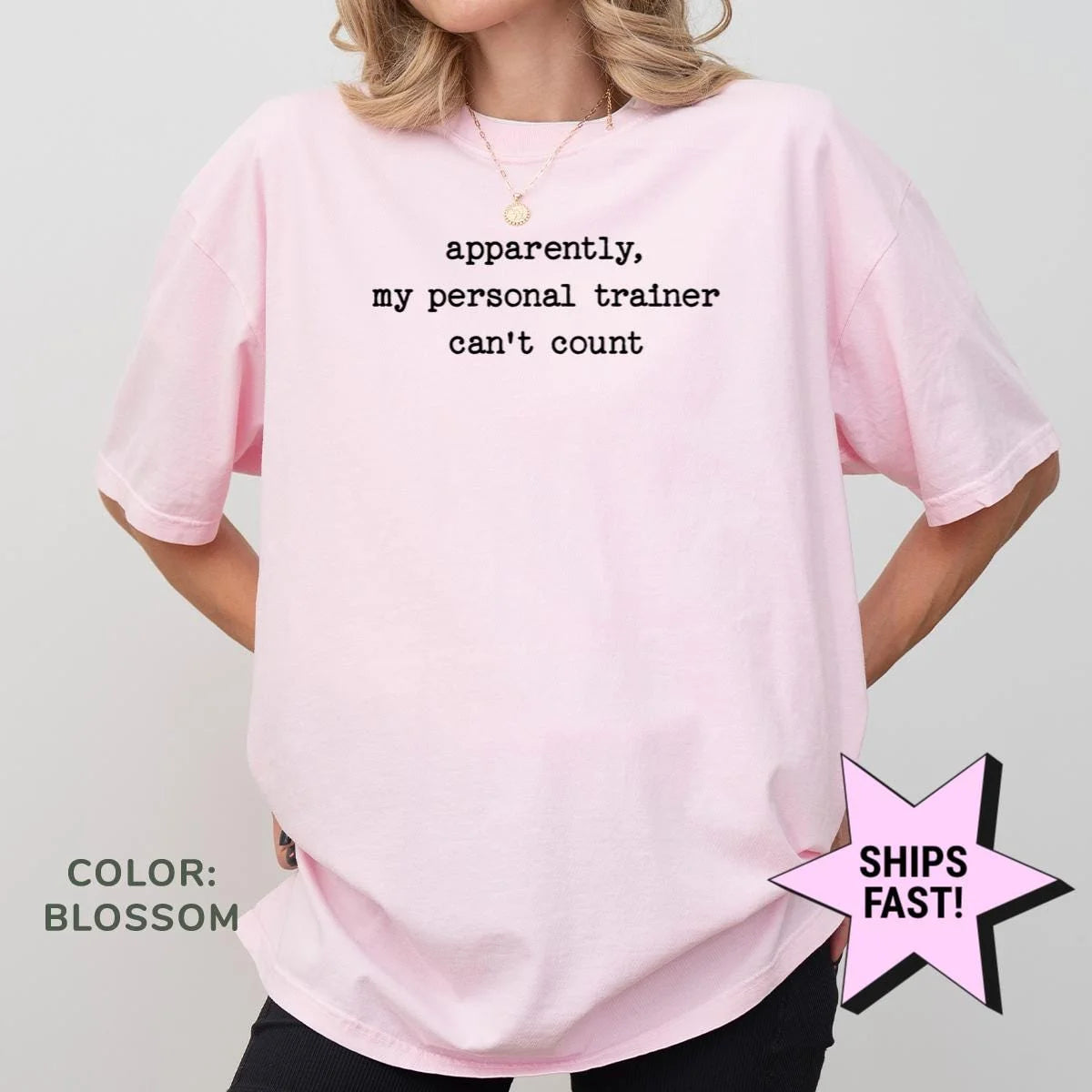 Woman in a Blossom pink Comfort Colors tee, hands on hips, with the personal trainer quote in small black typewriter type