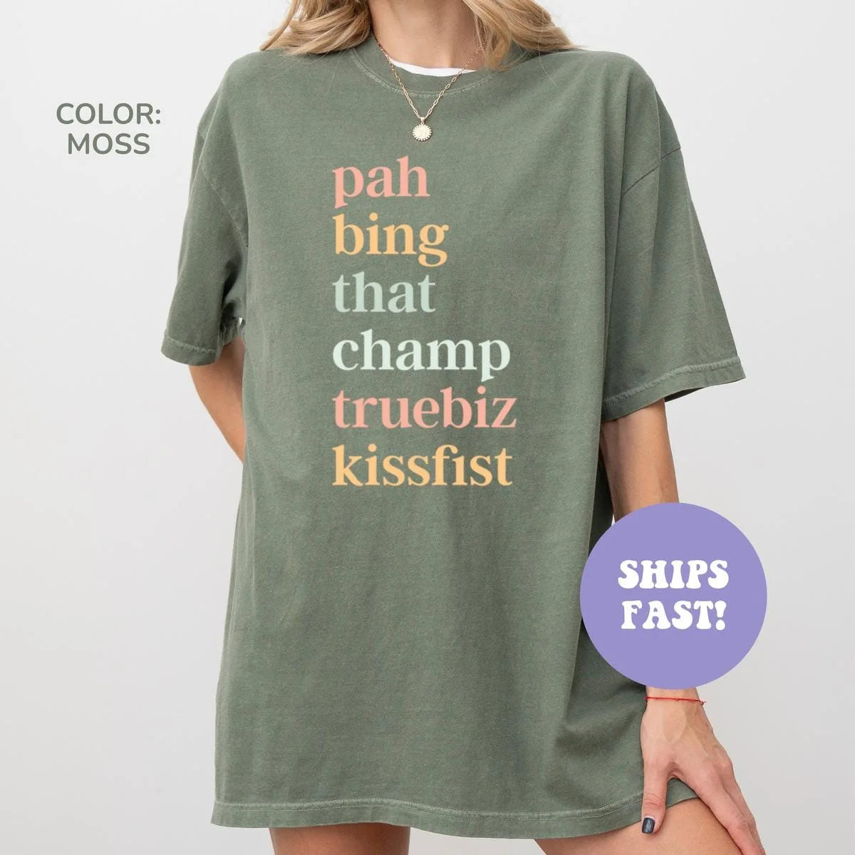 Woman in a Moss green Comfort Colors tee with the stacked words pah bing that champ truebiz kissfist in warm tones