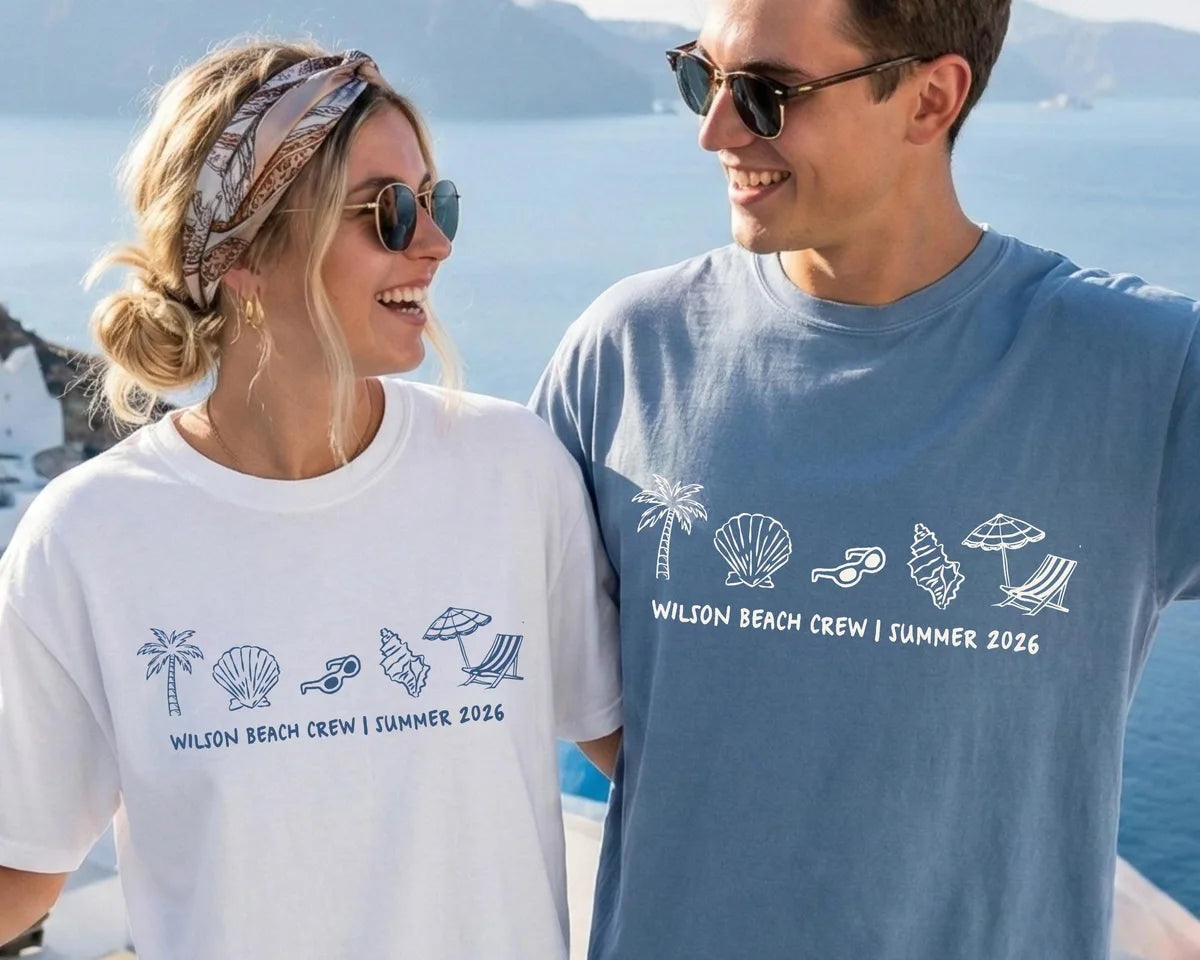 Woman in a White and man in a Blue Jean Comfort Colors tee by the sea, a row of beach icons above Wilson Beach Crew