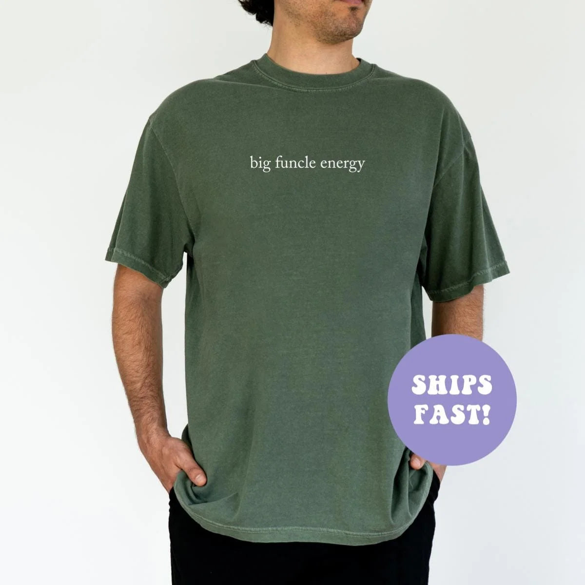 Man in a Moss green Comfort Colors tee, hand in pocket, with big funcle energy in small white serif lettering