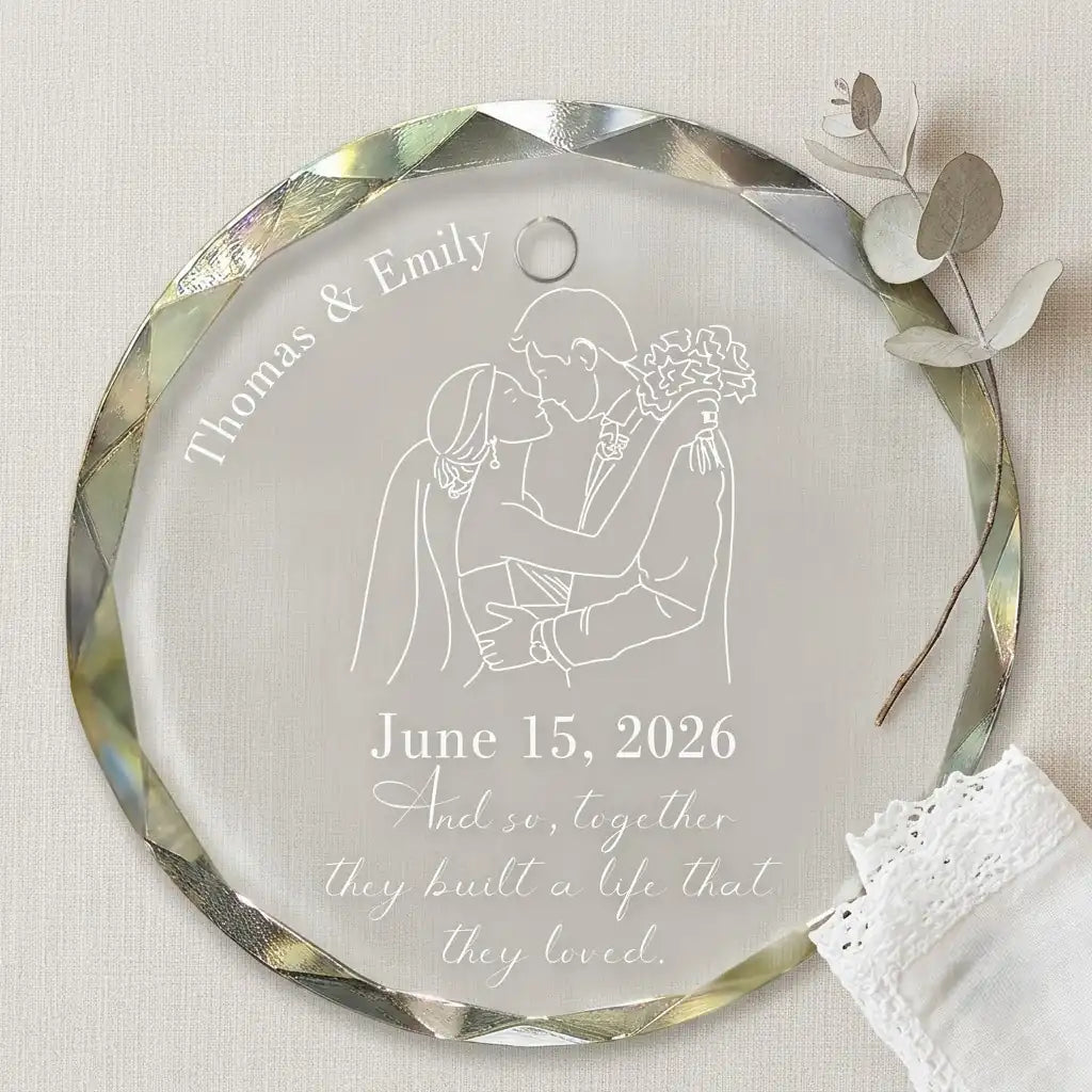 Clear glass round ornament laid flat on festive wooden surface with pine branches, pinecones and holiday decorations surrounding the wedding anniversary design