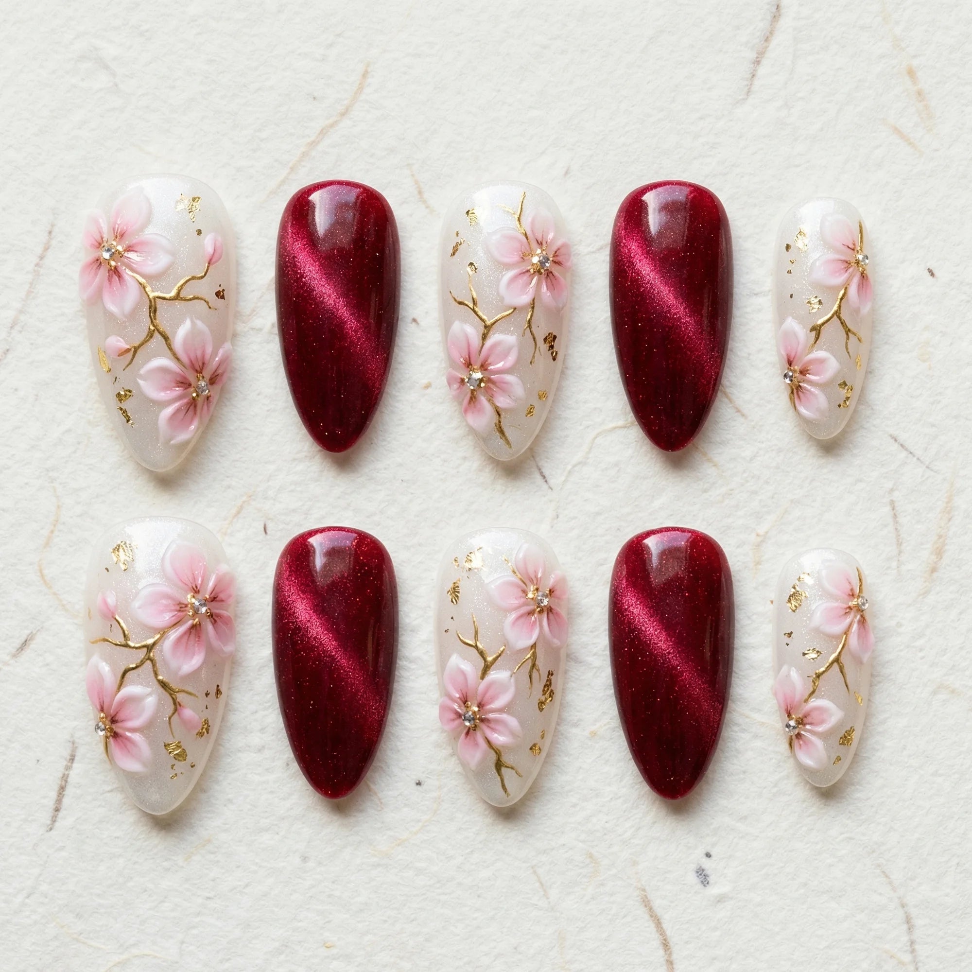 burgundy cat eye hand painted stiletto medium press on nails pink sakura flat lay 01