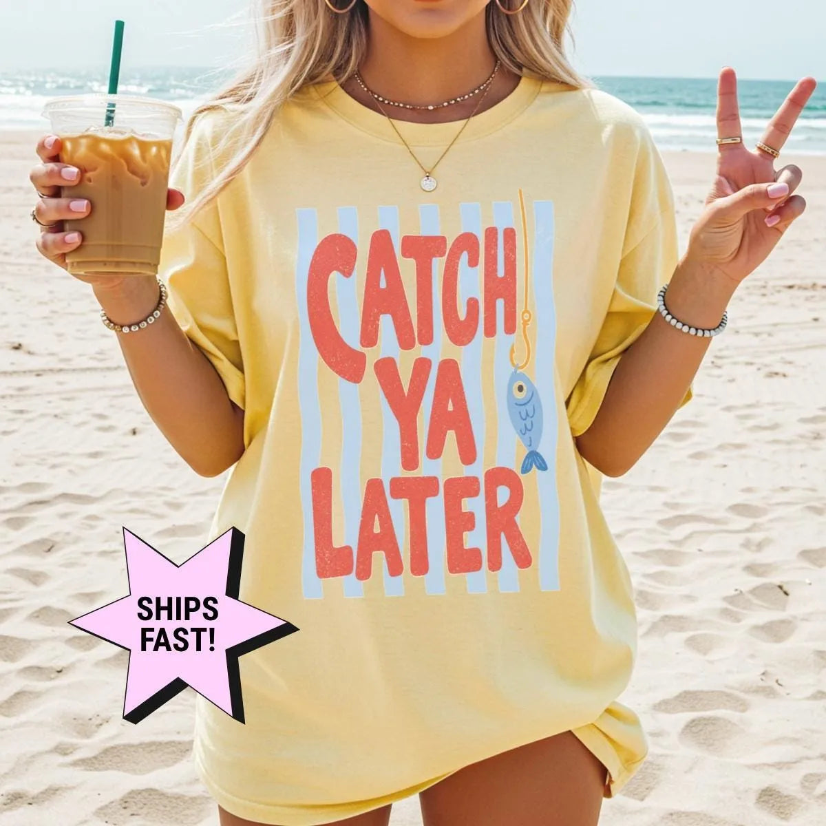Woman in a Butter yellow Comfort Colors tee on a beach, iced coffee in hand, red catch ya later text and a blue fish