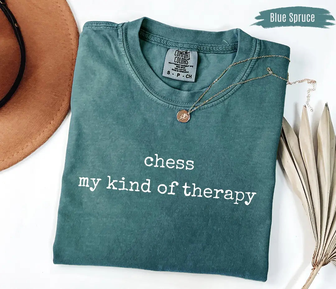 Blue Spruce Comfort Colors T-shirt with white 'chess my kind of therapy' lettering, folded mockup.