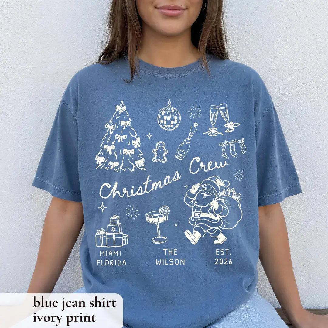 Woman in a Blue Jean Comfort Colors tee on a white wall, ivory christmas crew with bow tree, disco ball and gifts