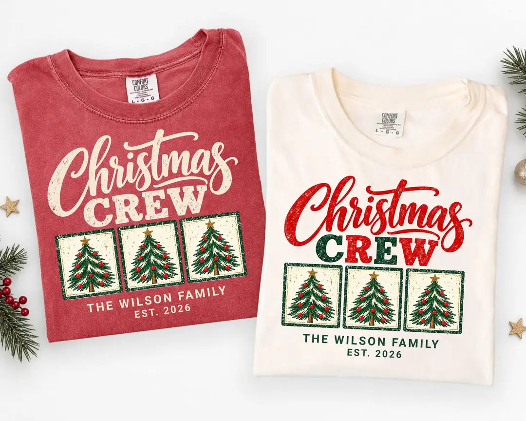 Folded Crimson and Ivory Comfort Colors tees with Christmas Crew above three framed trees and The Wilson Family Est. 2026