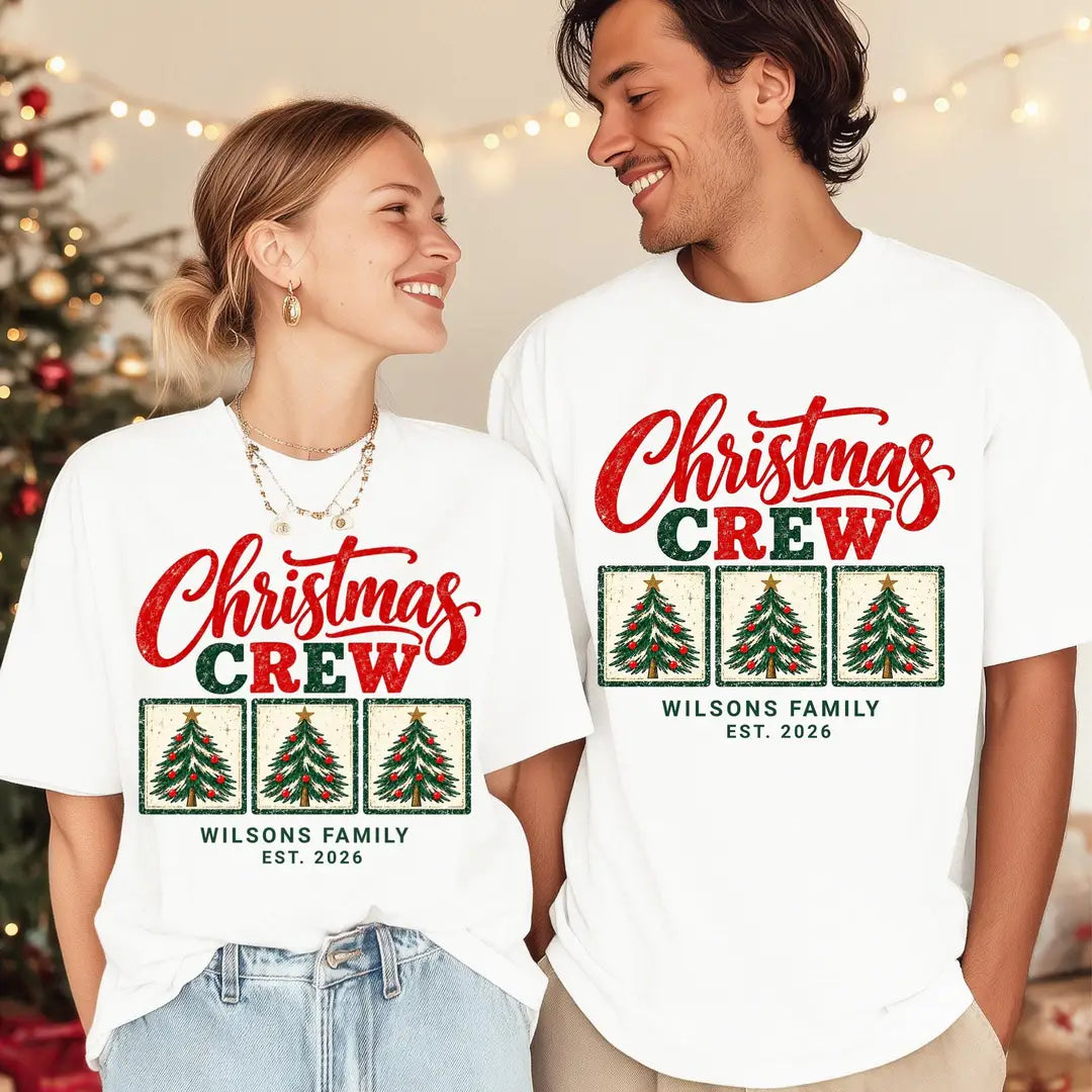 Woman and man in White Comfort Colors tees with string lights, red and green Christmas Crew over three framed trees