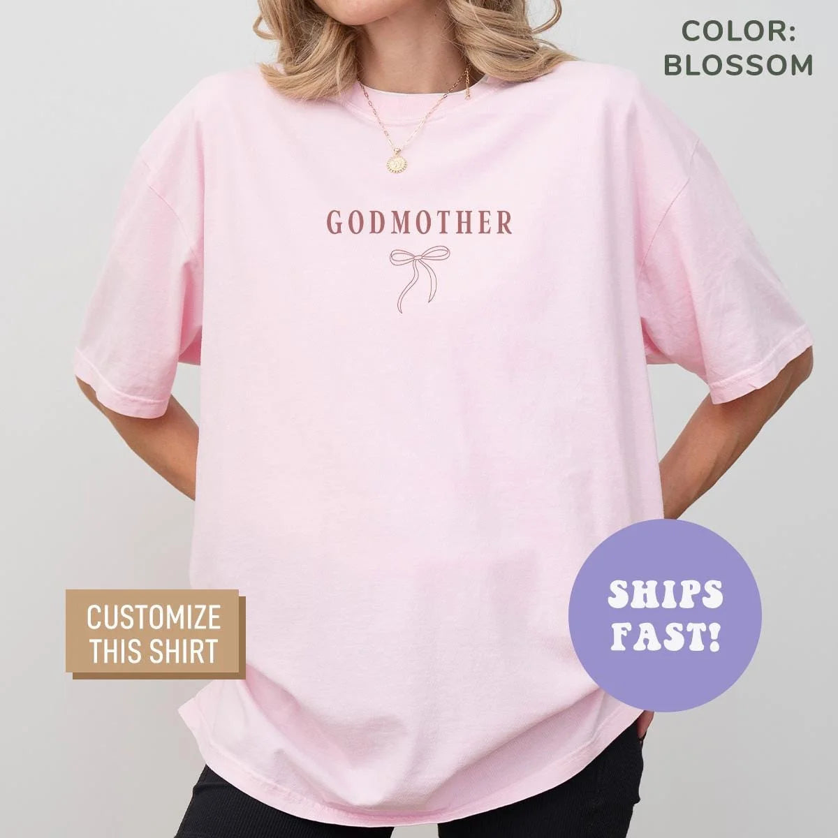 Woman in a Blossom pink Comfort Colors tee with rosy Godmother lettering above a small bow on the chest