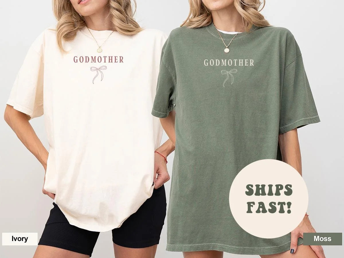 Two women side by side in Ivory and Moss Comfort Colors tees, each with small Godmother text above a line-art bow