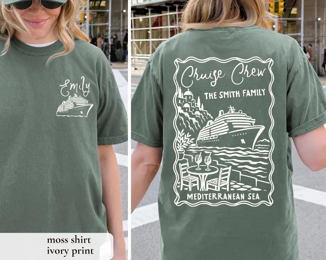Woman in a Moss green Comfort Colors tee, front with an ivory Emily and ship, back with the Cruise Crew cafe scene