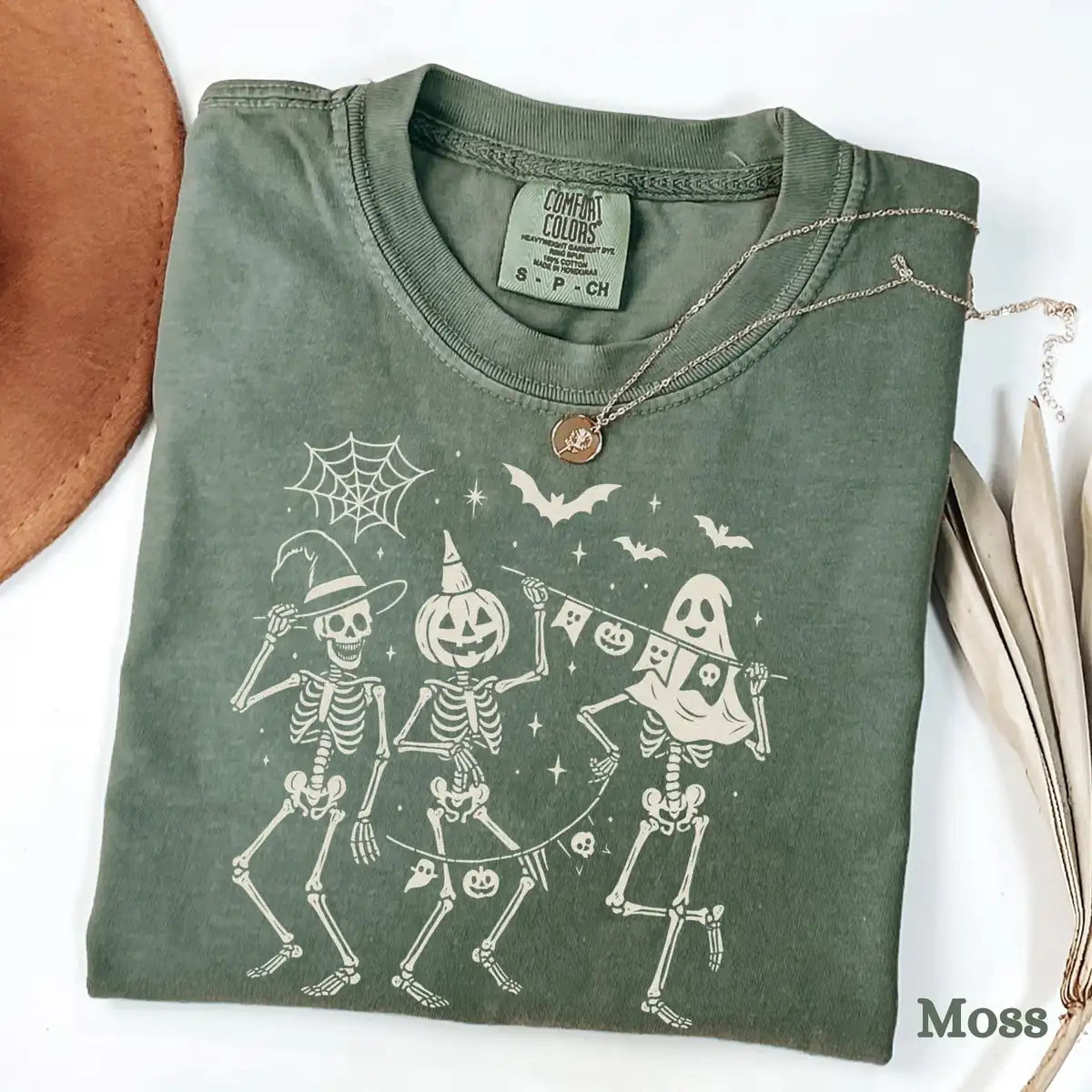Comfort Colors T-shirt in Moss color featuring dancing skeletons holding banner graphic