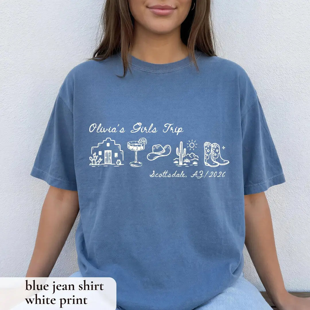 Woman in a Blue Jean Comfort Colors tee on a white wall, white Olivia's Girls Trip with adobe house, cactus and boots