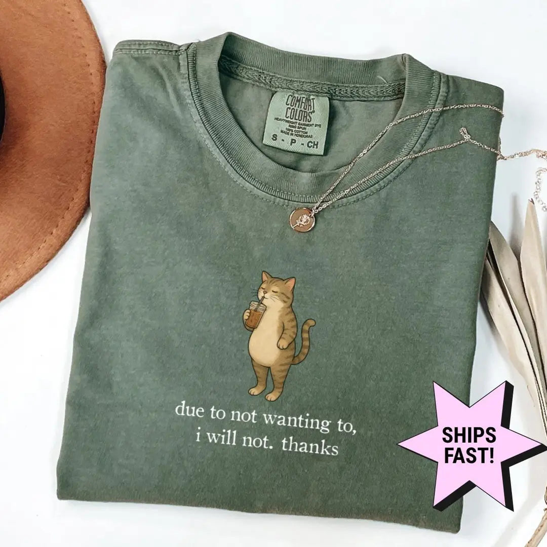Folded Moss green Comfort Colors tee with a tabby cat holding a drink and the words i will not. thanks in white