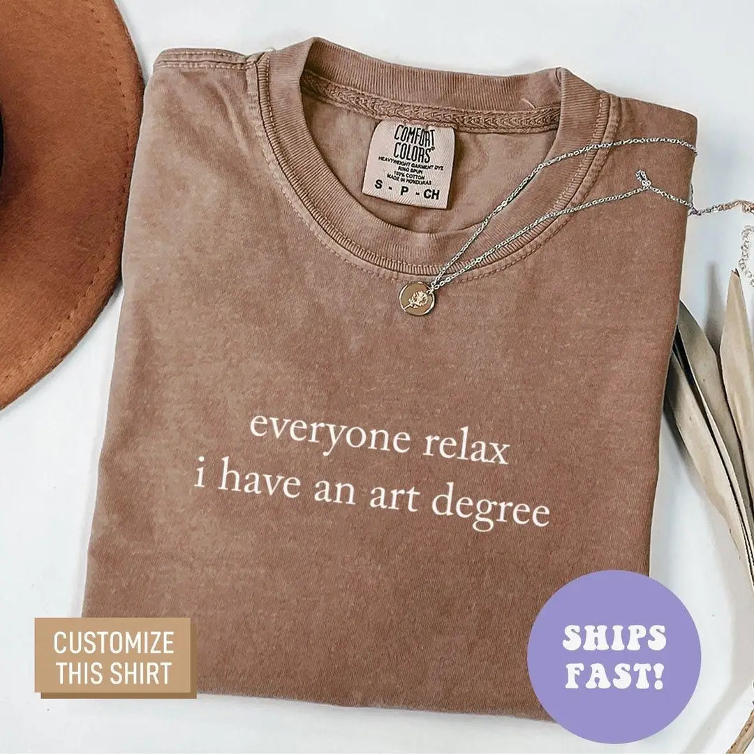 Folded Espresso brown Comfort Colors tee with the art degree quote in light serif letters, necklace at the neck