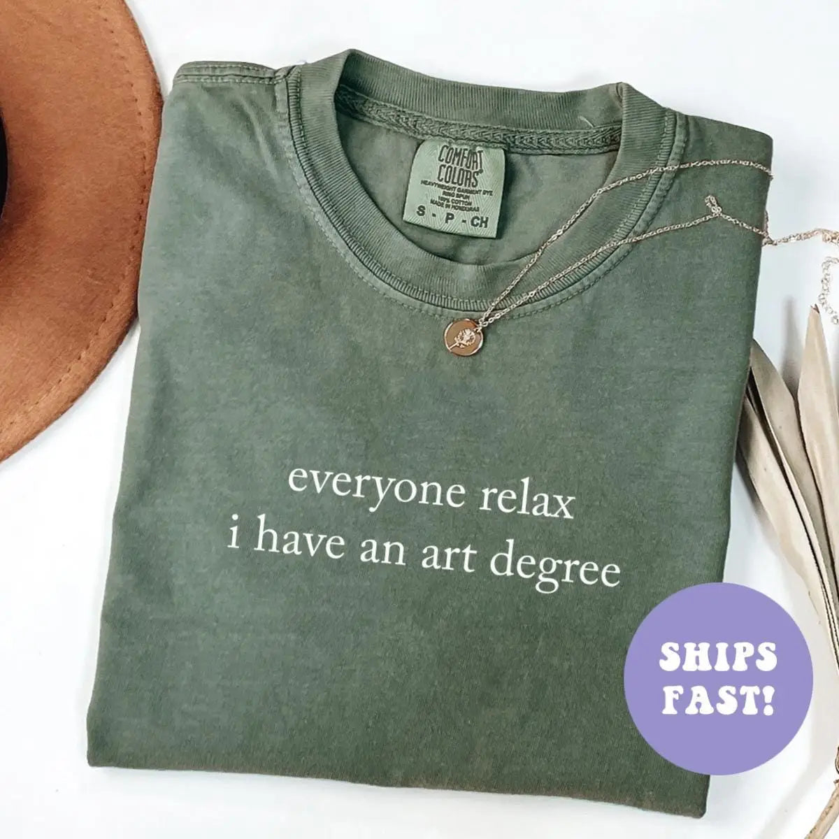 Folded Moss green Comfort Colors tee with everyone relax i have an art degree in white serif type