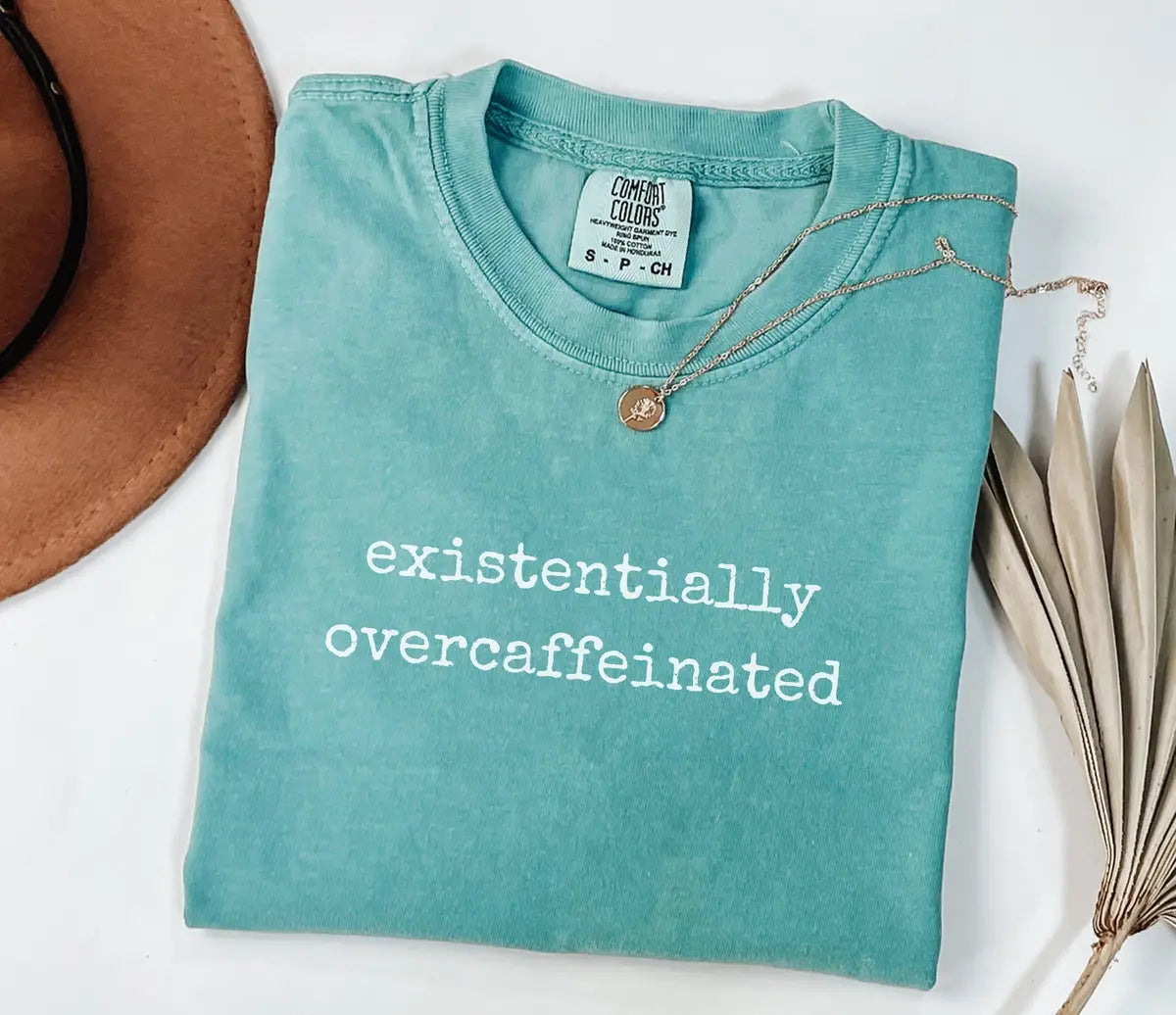 Seafoam Comfort Colors T-shirt with white Existentially Overcaffeinated lettering.