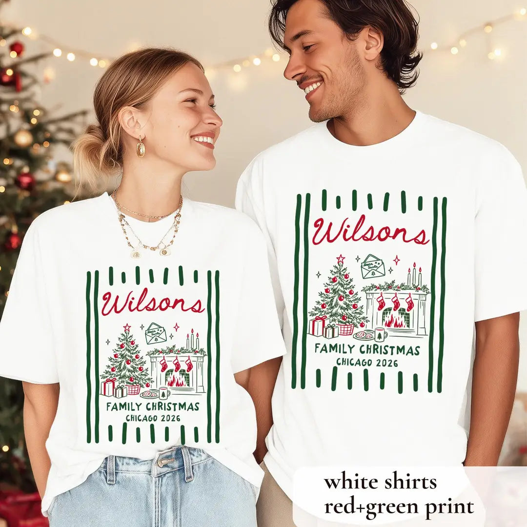 Woman and man by a christmas tree in White Comfort Colors tees, Wilsons script with fireplace, stockings and stripes