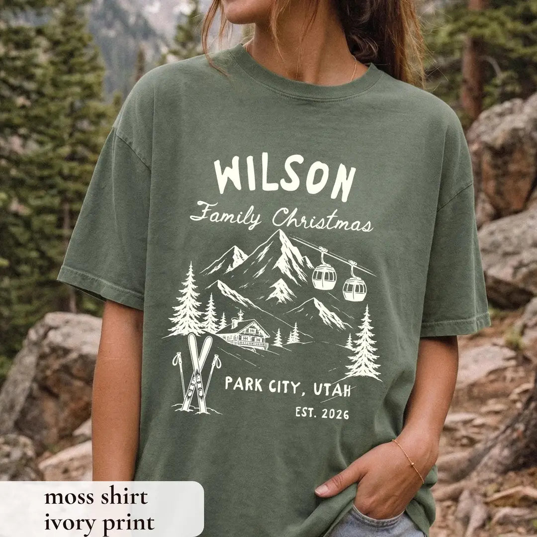 Woman in a Moss green Comfort Colors tee on a rocky trail, ivory Wilson Family Christmas with a lodge, skis and Park City