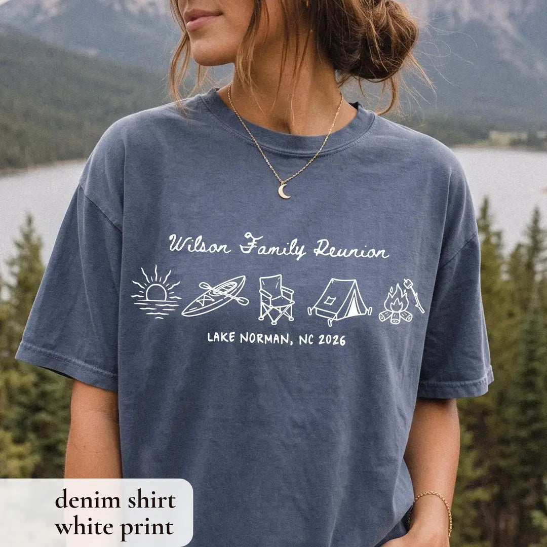 Woman in a Denim Comfort Colors tee above a mountain lake, white Wilson Family Reunion script with camping icons in a row