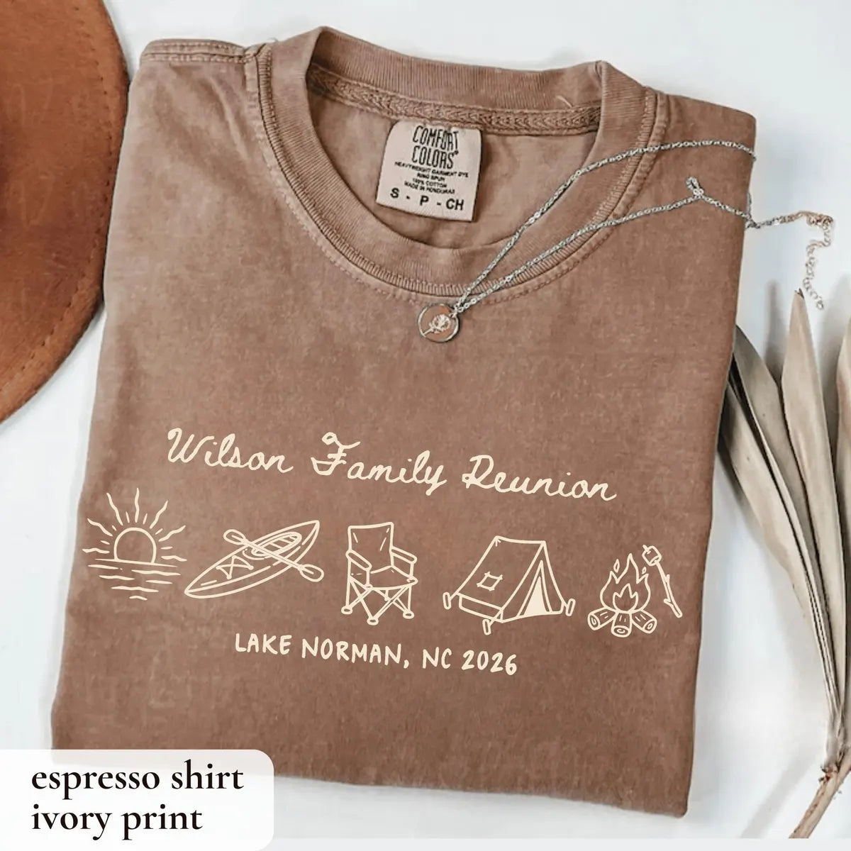 Folded Espresso brown Comfort Colors tee with ivory Wilson Family Reunion script, kayak, chair, tent and campfire icons