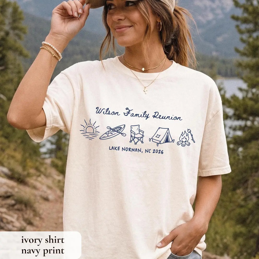 Woman in an Ivory Comfort Colors tee holding her cap, navy Wilson Family Reunion over icons and Lake Norman, NC 2026