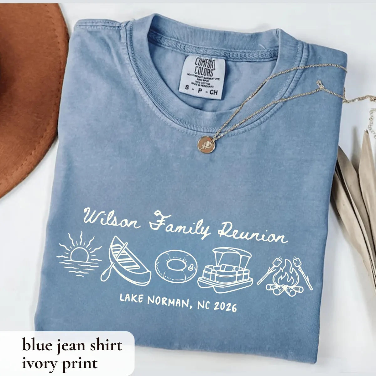 Folded Blue Jean Comfort Colors tee with ivory Wilson Family Reunion script, sunrise, canoe, tube and pontoon boat