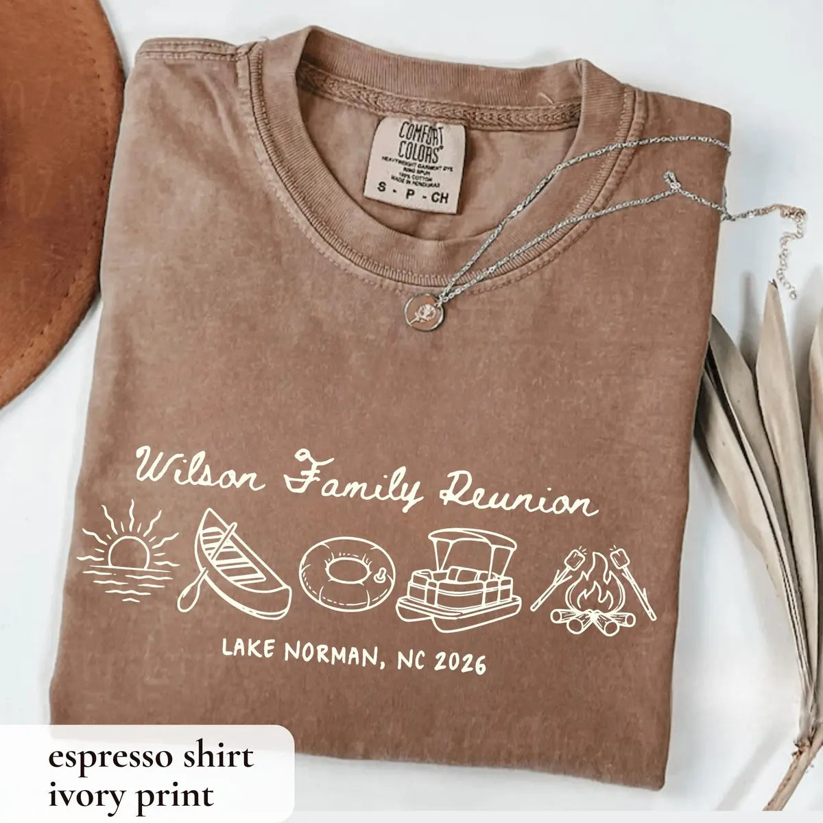 Folded Espresso brown Comfort Colors tee with ivory Wilson Family Reunion script, canoe, pontoon boat and campfire
