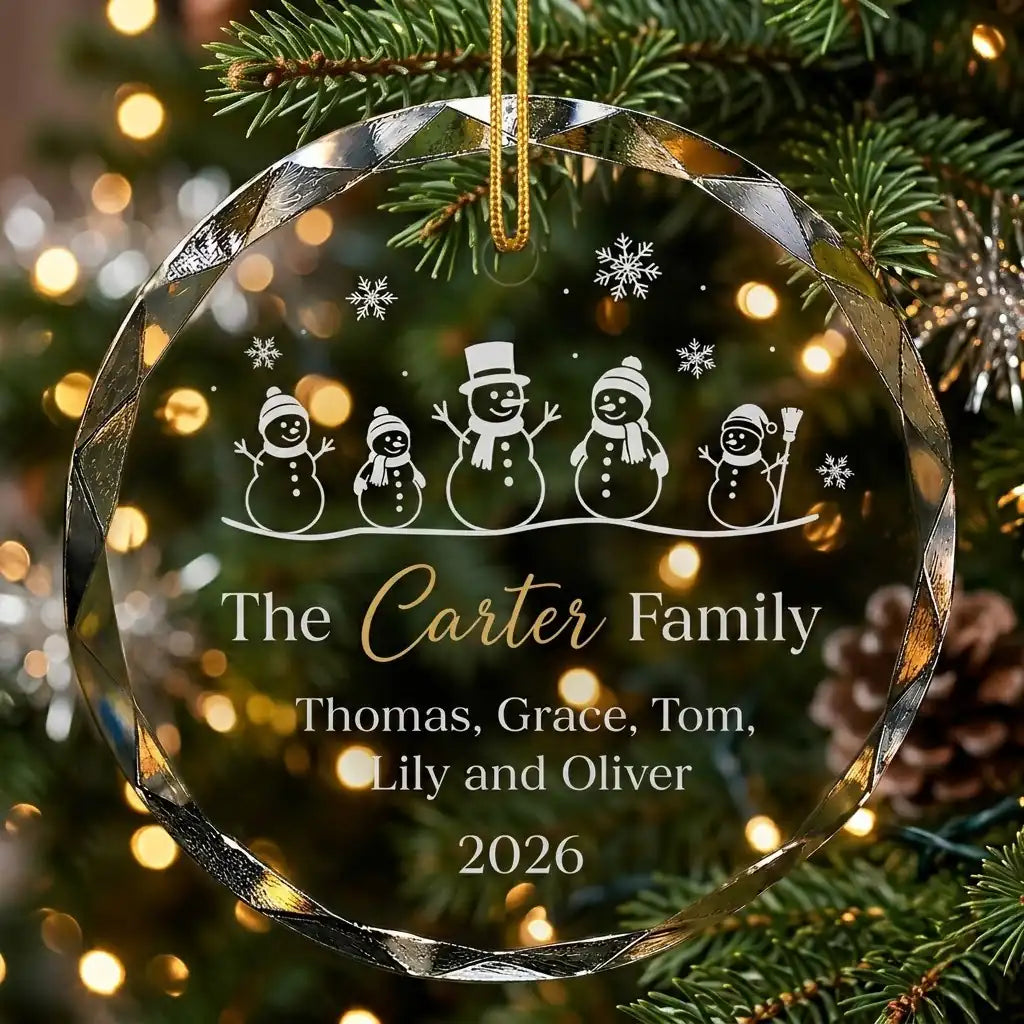 Personalized clear glass family christmas ornament displayed hanging on Christmas tree branch with warm sparkling holiday lights background