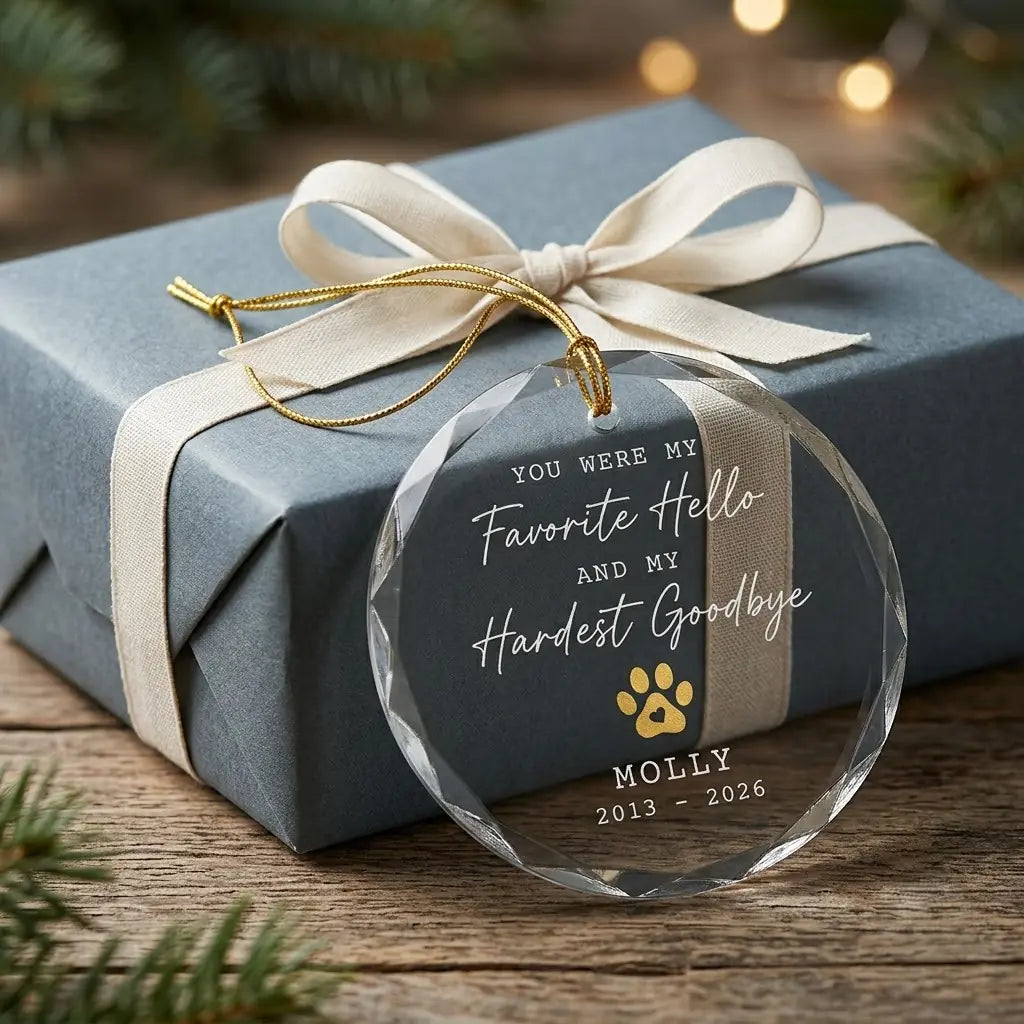 Personalized pet memorial glass ornament presented beside a wrapped holiday gift box on rustic wooden background