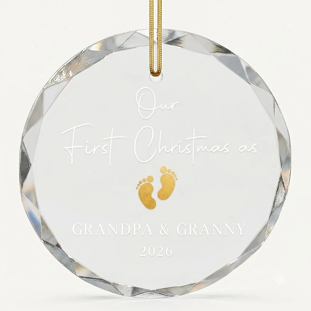 Beveled edge clear glass round ornament featuring printed gold baby footprint pair graphics, custom text Our First Christmas as Grandpa Granny and personalized details hanging on gold ribbon