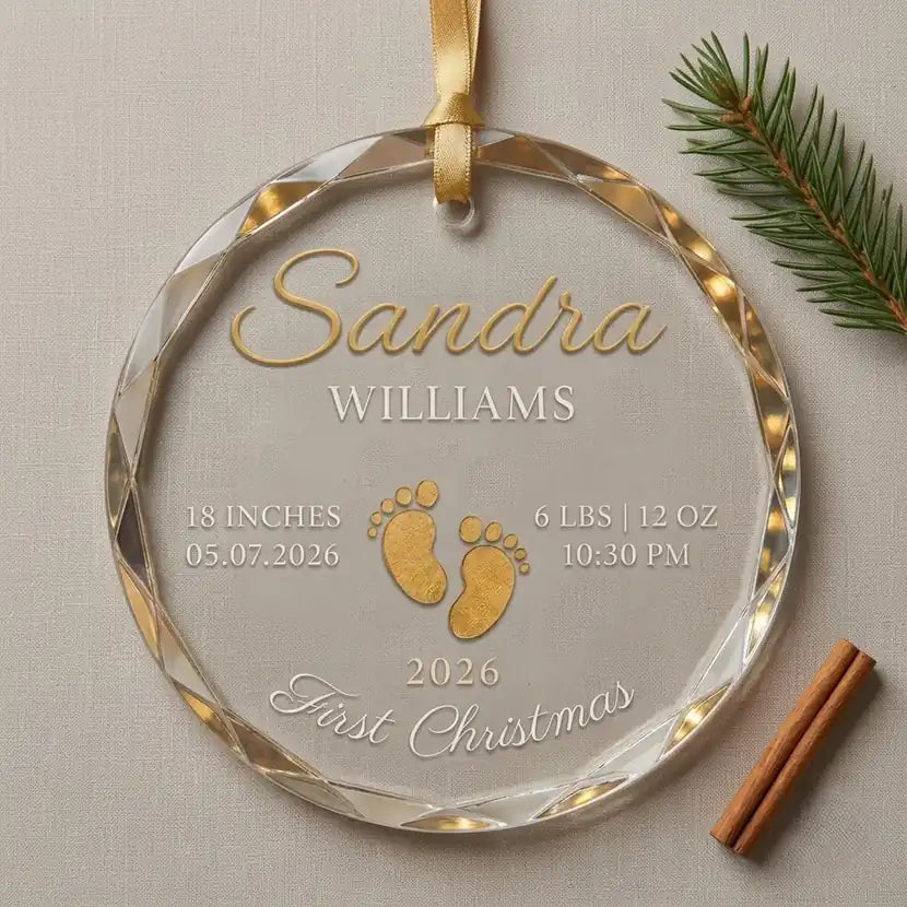 Clear glass round ornament featuring gold baby footprints and custom birth statistics details with flatlay view