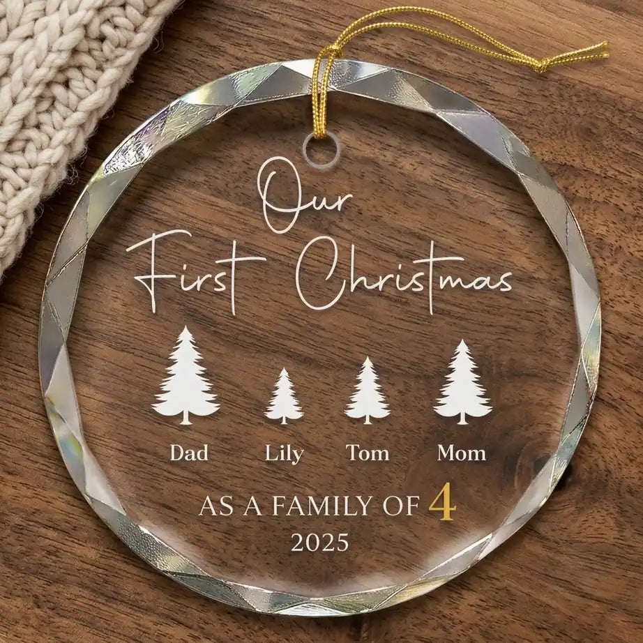 Clear glass round ornament laid flat on festive wooden surface with pine branches, pinecones and holiday decorations surrounding the family of 4 design
