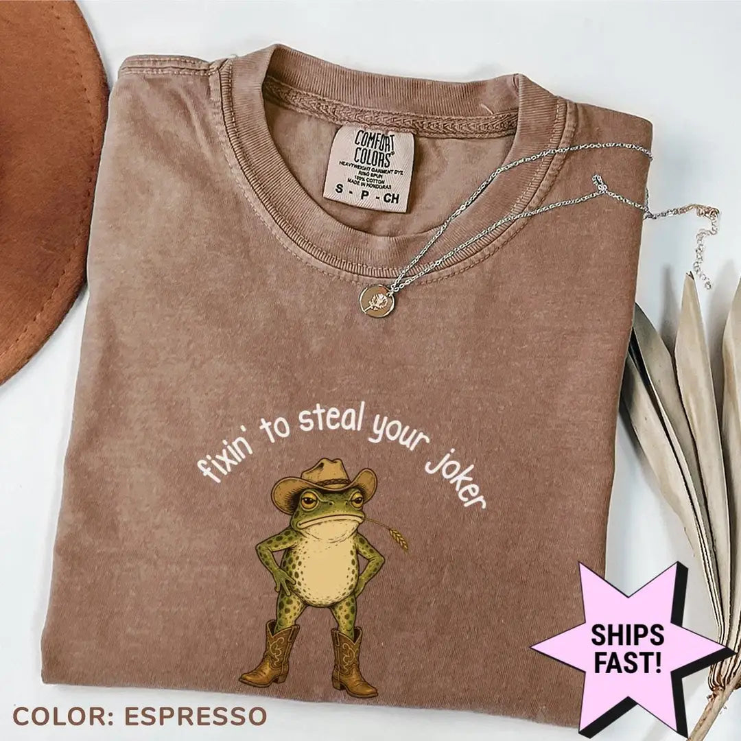 Folded Espresso brown Comfort Colors tee with a cowboy frog in tan boots beneath arched fixin' to steal your joker text