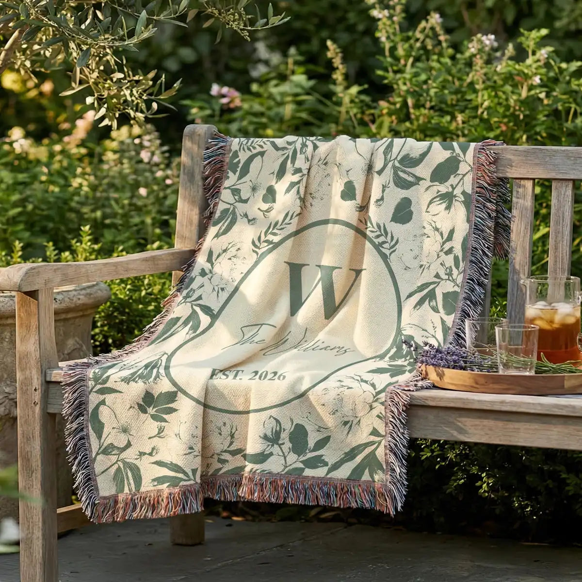 Close-up of the personalized floral toile woven blanket with monogram and fringe detail