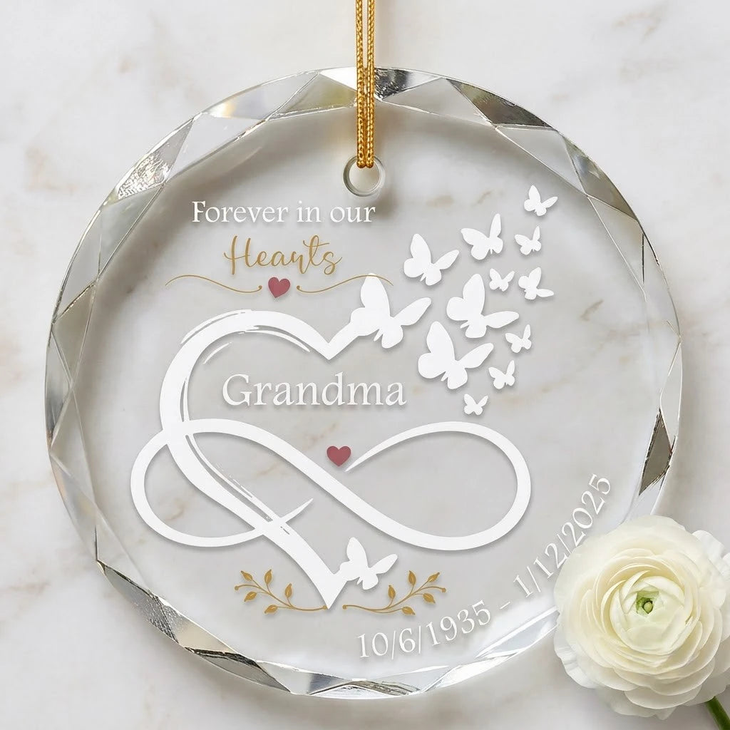 Clear glass round ornament laid flat on festive wooden surface with pine branches, pinecones and holiday decorations surrounding the grandma memorial design