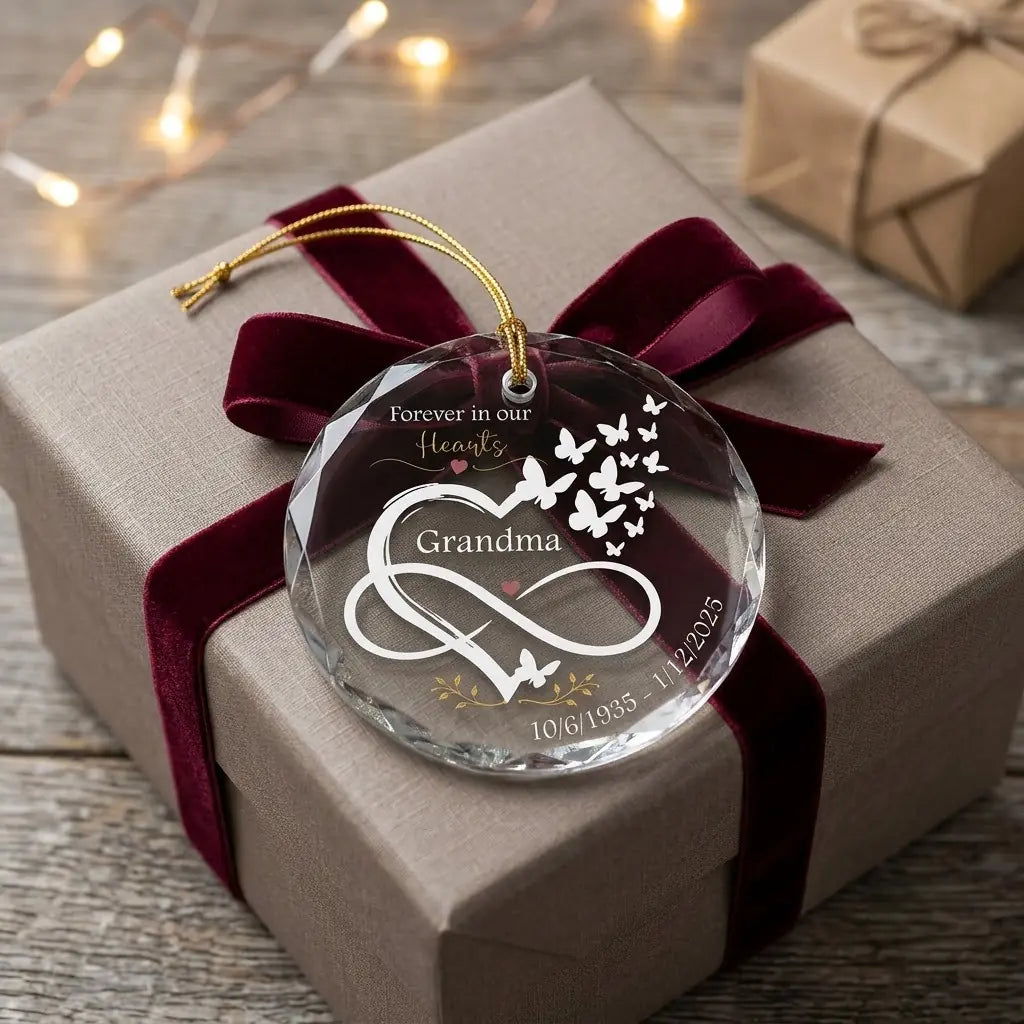 Personalized grandma memorial glass ornament presented beside a wrapped holiday gift box on rustic wooden background