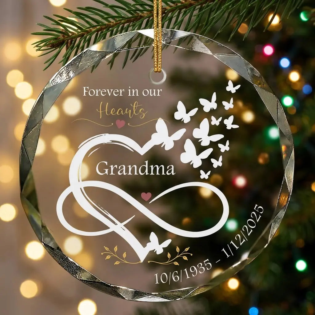 Personalized clear glass grandma memorial ornament displayed hanging on Christmas tree branch with warm sparkling holiday lights background