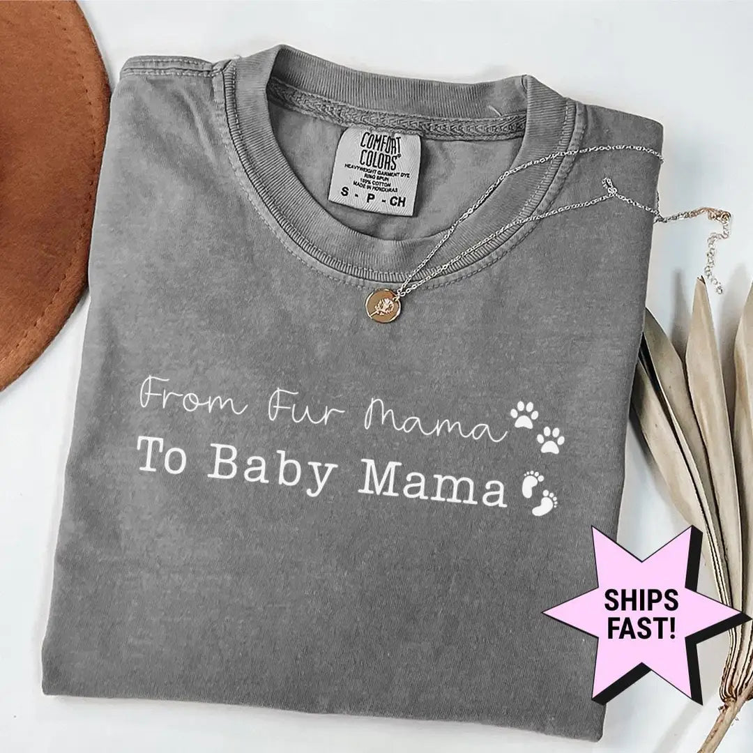 Folded gray Comfort Colors tee with white from fur mama to baby mama text, a paw print and baby feet, necklace on the collar