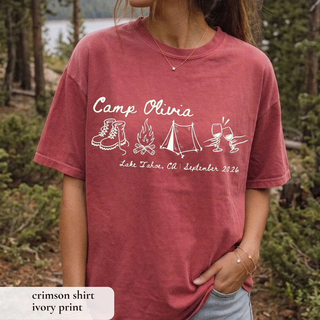 Woman in a Crimson Comfort Colors tee in the woods, ivory Camp Olivia script and a Lake Tahoe, CA September 2026 line